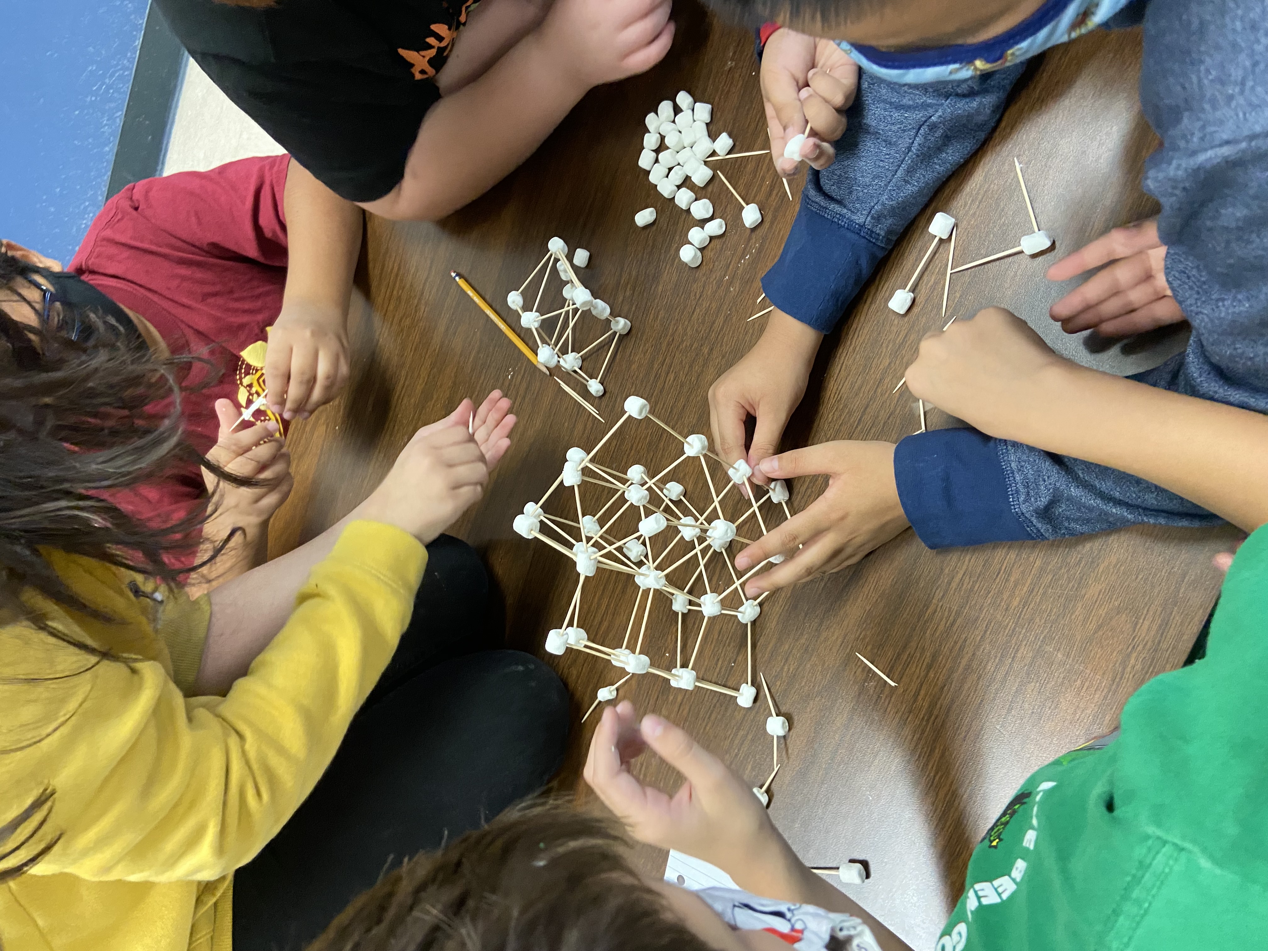 Students working on a project with toothpicks and marshmallows. 
