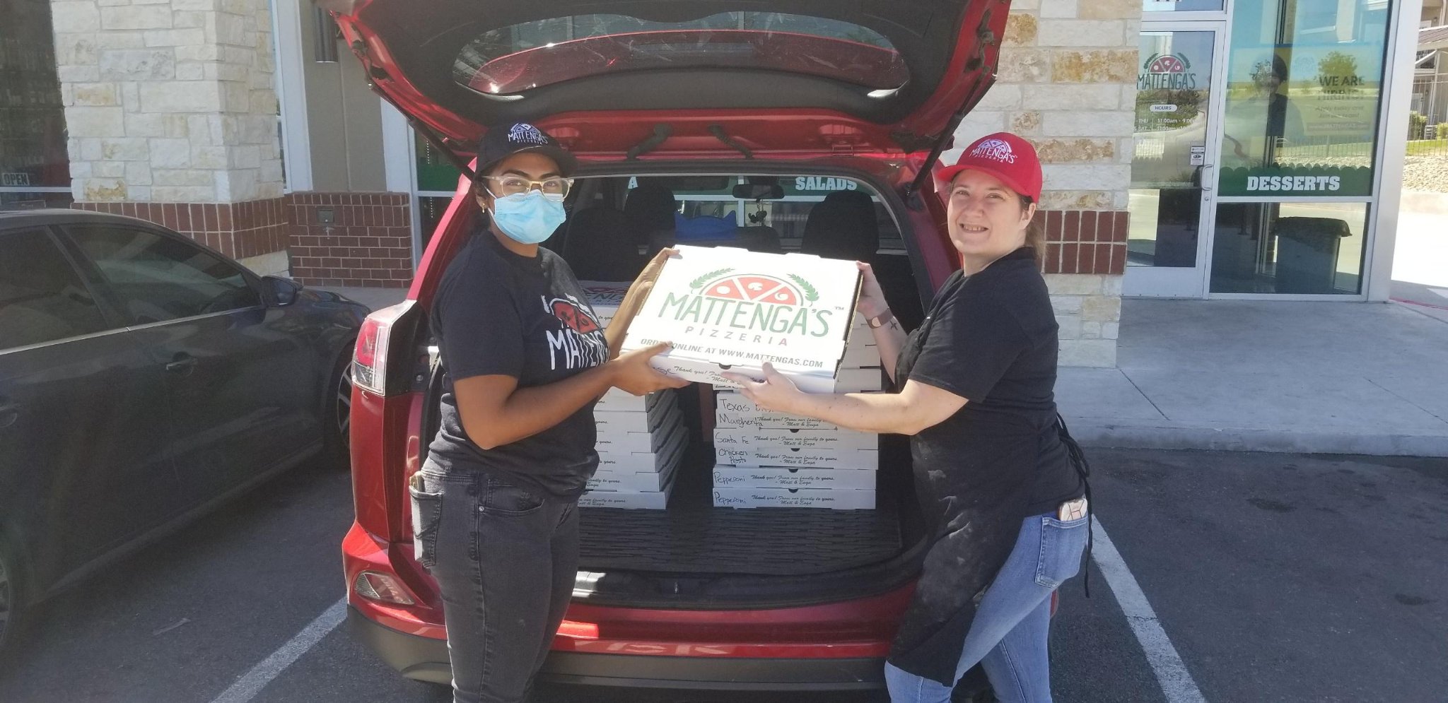 Two female employees of Mattenga's Pizzeria delivering pizza to Lewis Elementary.