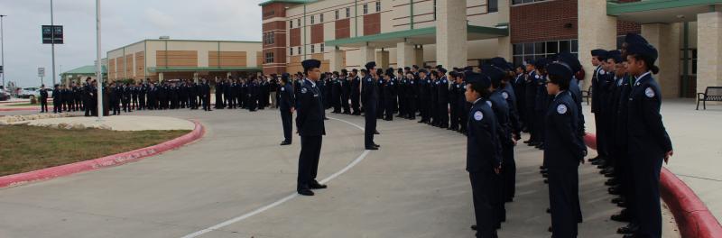 JROTC standing in attention outside the campus.