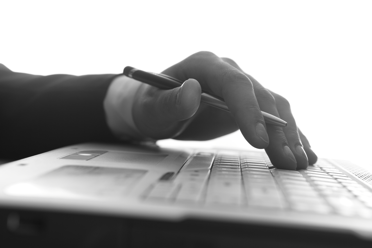 Hand holding pen using laptop