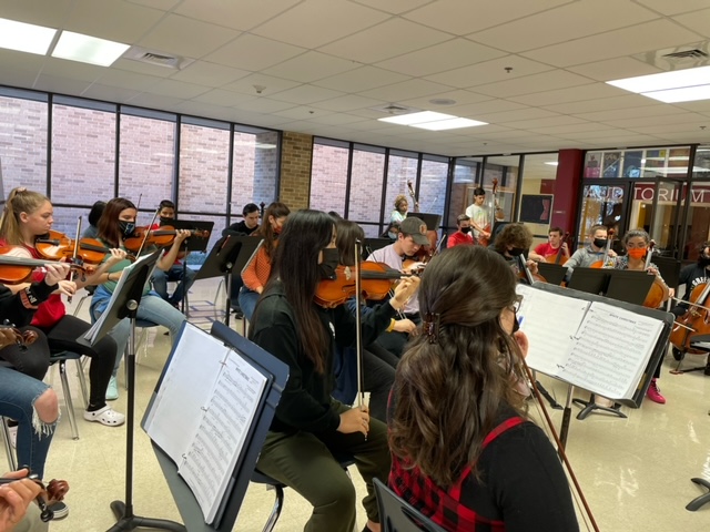 Rear view of Taft orchestra students playing instruments in school foyer