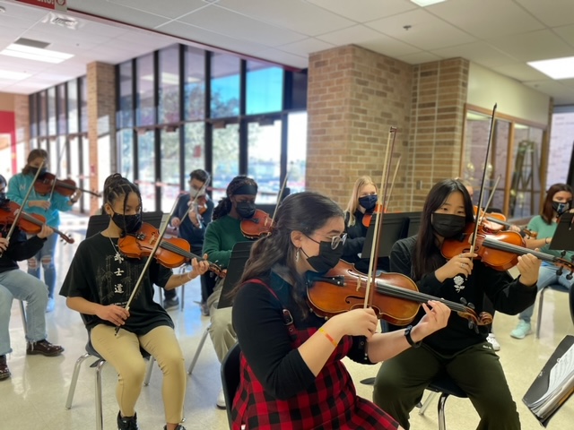 Front view of Taft orchestra students playing instruments in school foyer