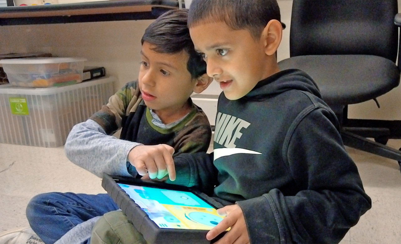 Two students working together on a tablet in the classroom.