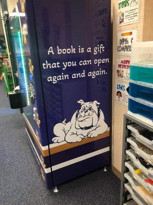 Pic of right side of Book Vending Machine with "A book is a gift that you can open again and again" quote and Helotes Bulldog logo