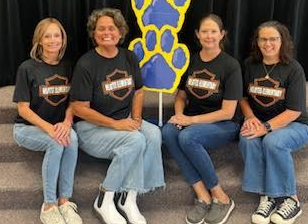 Pic of Helotes Elementary Third Grade Team sitting on the stage steps with big blue bulldog paws behind them