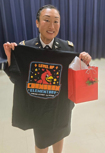 A military officer, in uniform, holding a carnahan t shirt