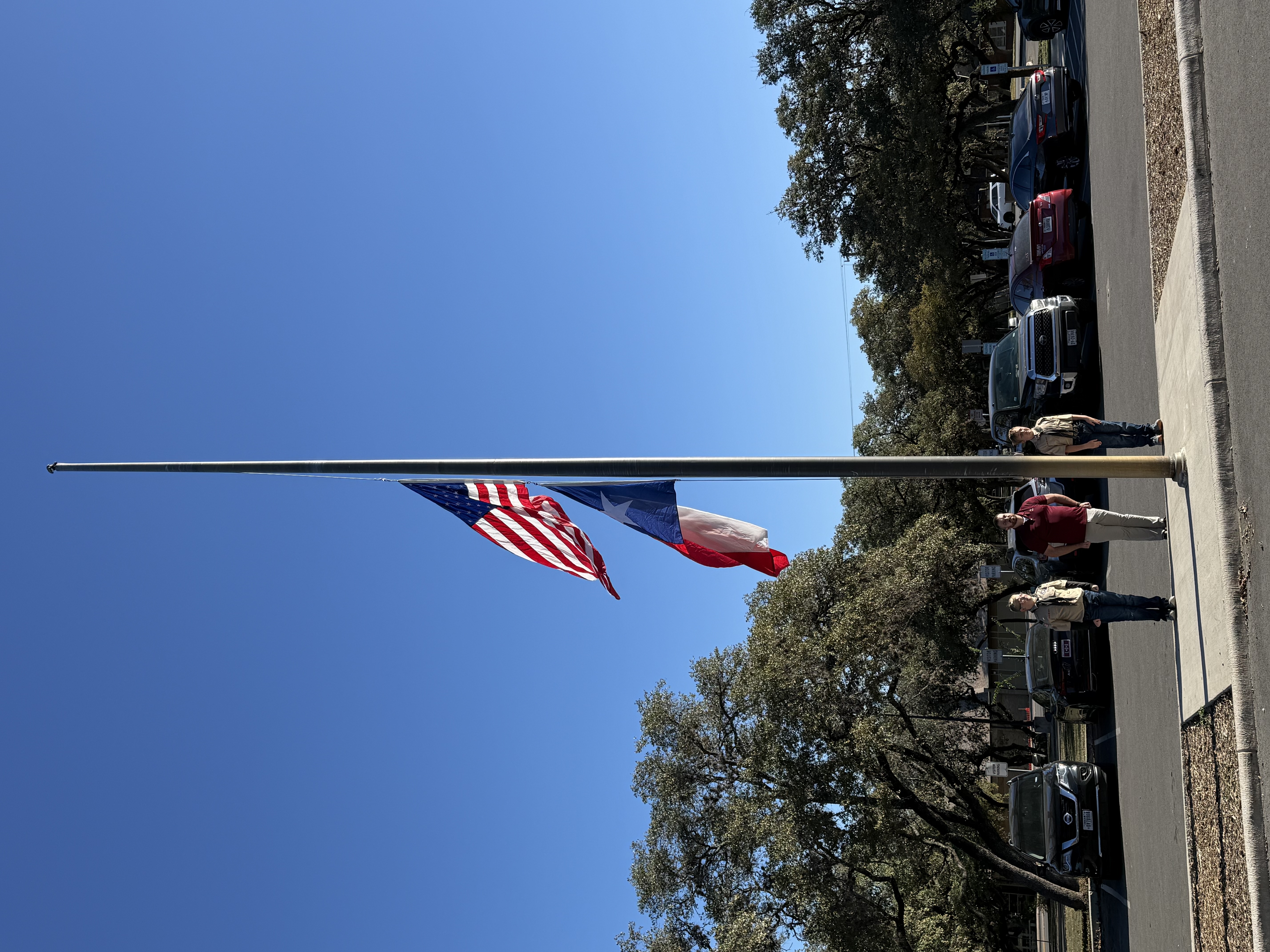 picture of the american and texas flag rising on the flag pole