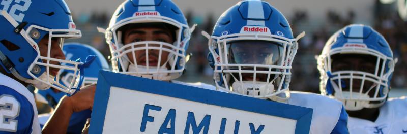 football players holding a sign the says "family"
