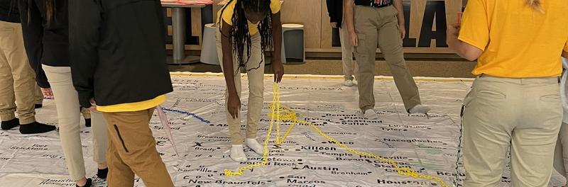 Maps on the floor with students walking on it
