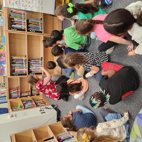 Mrs. Scherwitz showing kindergarten friends how to look for a book.