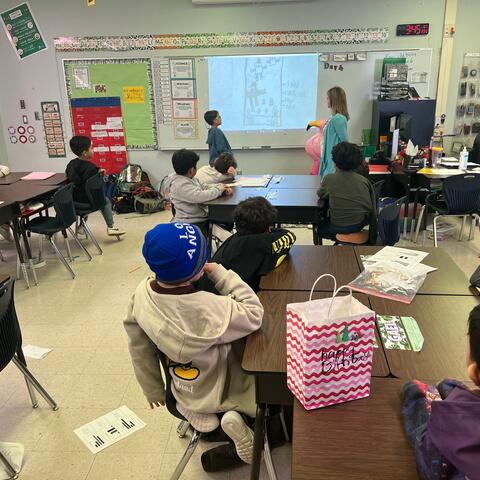 Cardboard arcade students learning from student presenter on his design.
