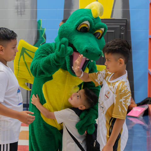 back to school Rhodes Elementary dragon mascot hugging three boys