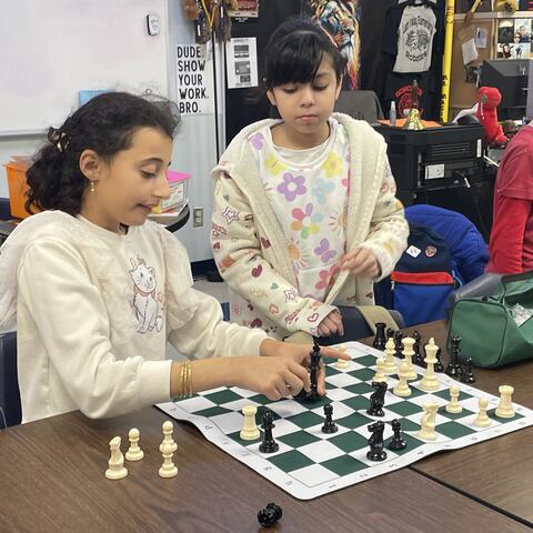 Students are shown playing chess. 
