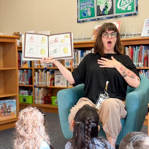 Ms. Mosley reading to students with a surprised look on her face.