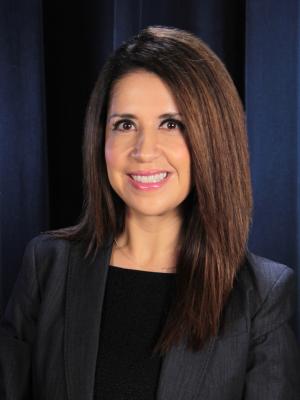 Principal Espinoza sitting smiling wearing a black professional suit.