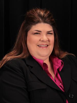 Principal Kendra Merrell wearing a black suite with fuchsia shirt.