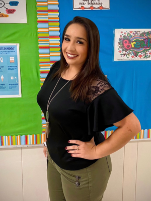 Portrait of Ms. Gonzaba posing infront of a colorful bulletin board