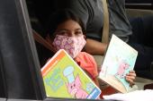 Little girl in mask holds up books in car