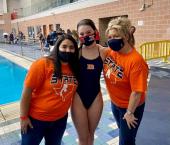 Brandeis diver poses with her coaches by the pool at state diving competition 