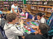 Why STEM photo of students interacting at a table in the library.